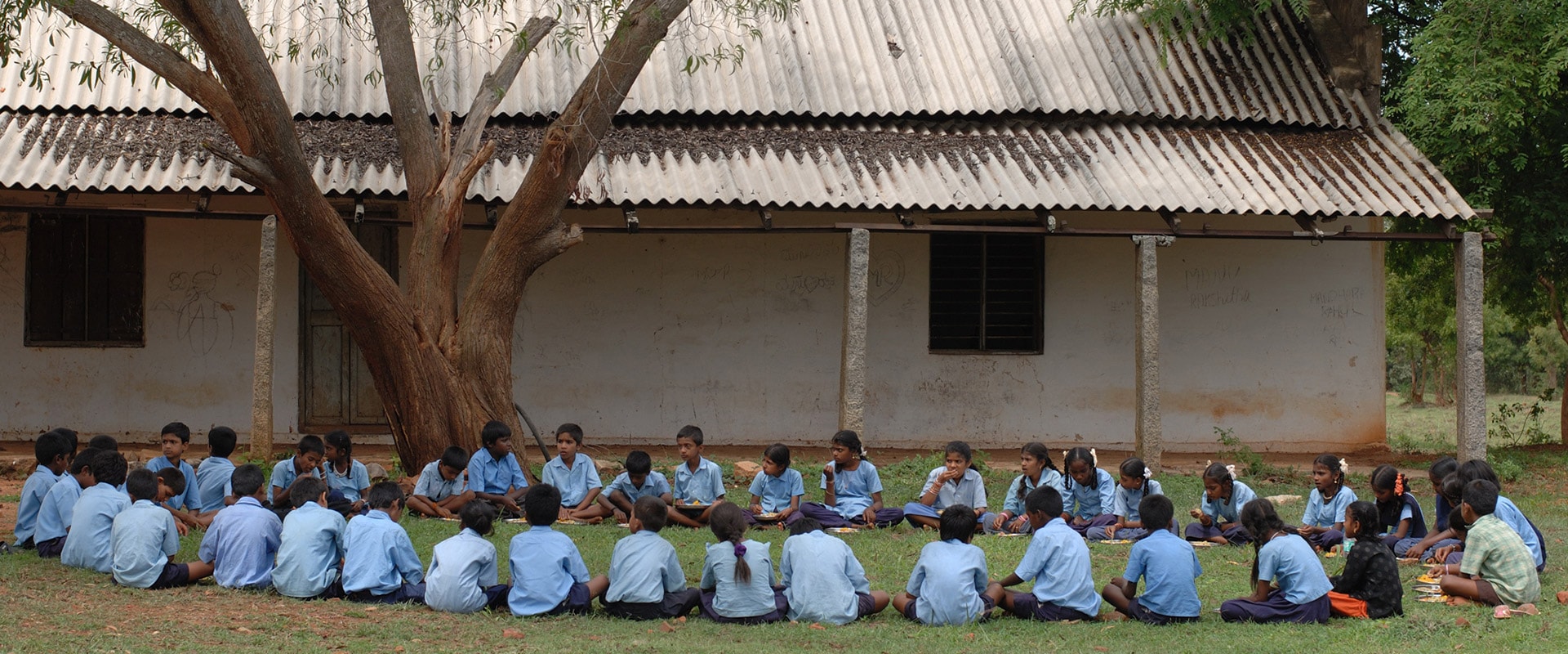 Children in a huge circle in the lawn eating an Akshaya Patra-provided meal.